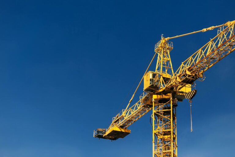 construction crane tower in sun light beams on background of blue sky